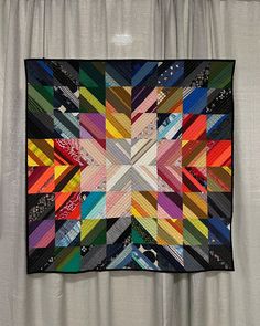 a multicolored patchwork quilt hanging on a curtain