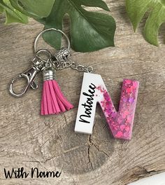 a pink and white letter keychain with tassels hanging from it's side