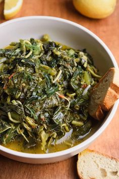 a white bowl filled with greens and bread