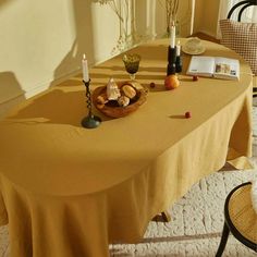 the table is covered with a yellow cloth and has candles on it, along with other items