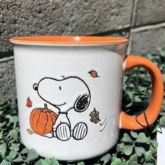 a white and orange coffee mug with a cartoon character on it sitting in the grass