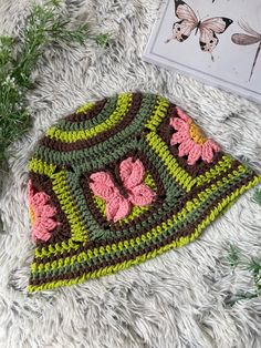 a crocheted hat sitting on top of a white blanket next to a plant