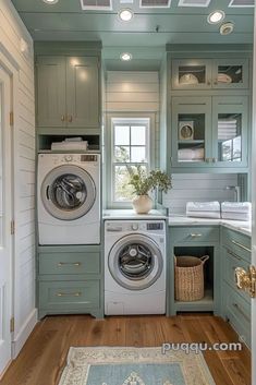 a washer and dryer in a small room with wood flooring, green cabinets and white walls