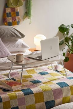 a laptop computer sitting on top of a bed next to a cup and saucer