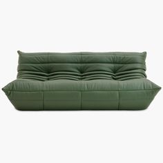 a green leather couch sitting on top of a white floor