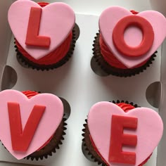 four cupcakes with pink frosting and red icing that spell out the word love