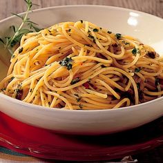 a white bowl filled with pasta and garnished with herbs on a red plate