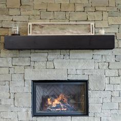 a fireplace with a fire in it and some shelves on the wall above it that are made out of stone