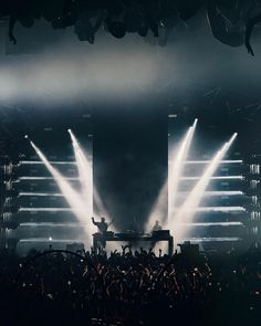 the stage is lit up with white lights and some people are standing on either side