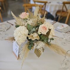 a centerpiece with flowers and feathers on a table at a wedding reception in a banquet hall