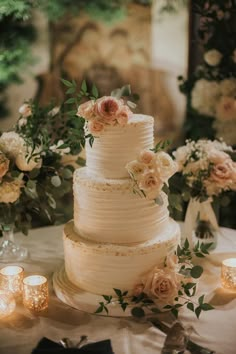 a wedding cake sitting on top of a table next to some candles and flower arrangements