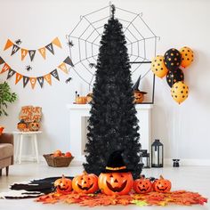 a decorated halloween tree with pumpkins and balloons on the floor in front of it