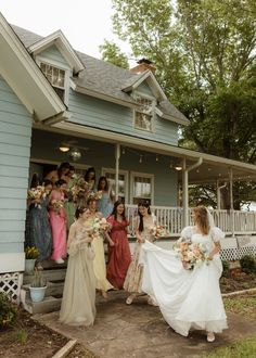 a bride and her bridal party in front of a blue house on the porch