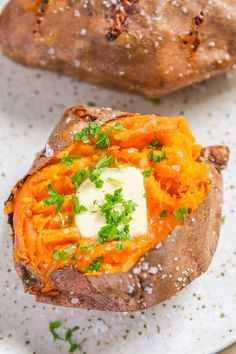 baked sweet potatoes with butter and parsley on top, served on a white plate