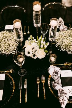 the table is set with white flowers and silverware