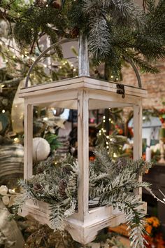 a white lantern hanging from a tree in a room filled with christmas decorations and greenery