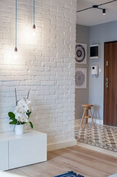 a living room with white brick walls and wood flooring on the side, along with an area rug