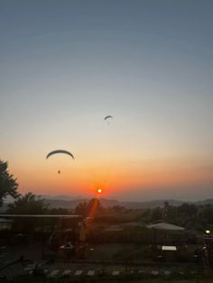 two kites flying in the sky at sunset