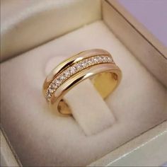 a gold ring with two rows of diamonds on it in a box for someone to see