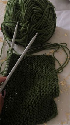 someone is knitting yarn on the table with two crochet hooks and a pair of scissors