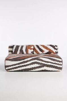 a brown and white striped purse sitting on top of a table next to a wall