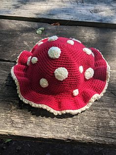 a red hat with white polka dots sitting on top of a wooden bench