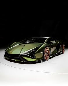 a green sports car is on display in a dark room with white floor and walls