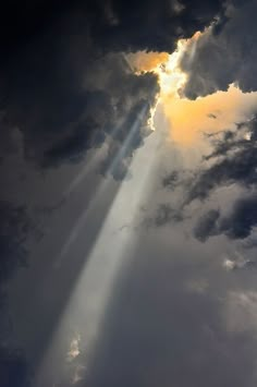 an airplane flying through the sky with sun rays coming out from behind it and clouds in the background