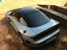 a silver sports car parked in the dirt