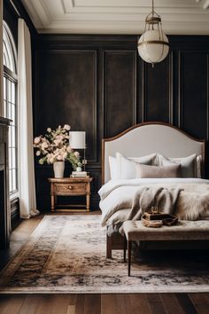 a bedroom with dark wood paneled walls and white bedding, an upholstered footstool