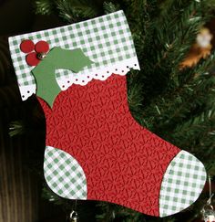 an ornament hanging from a christmas tree decorated with green and red plaid fabric