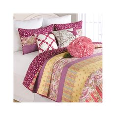 a pink flower is sitting on top of a bed with colorful sheets and pillow cases