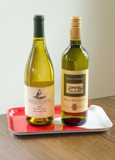 two bottles of wine sitting on top of a red and white tray next to each other