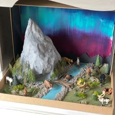 an open cardboard box with toy animals and rocks in the inside that is filled with water