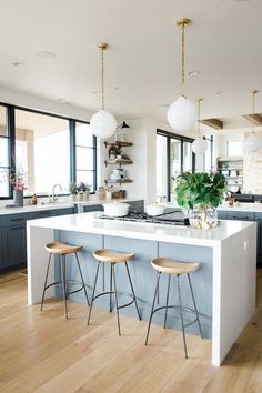 a large kitchen with two stools next to an island in the middle of it