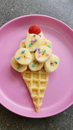 a waffle with bananas and strawberries on it is sitting on a pink plate