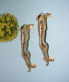 two metal seahorses sitting on top of a blue wall next to a potted plant