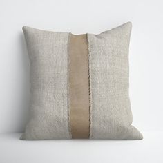 a white pillow with two brown stripes on the front and back of it, against a white wall