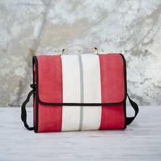 a red and white striped purse sitting on top of a wooden table next to a stone wall