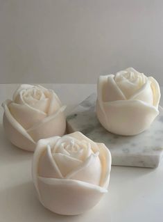 three white roses sitting on top of a marble slab