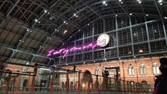 the inside of a train station with a large clock on it's wall and people walking around