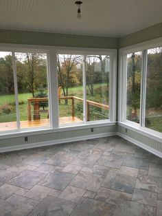 an empty room with large windows and wooden bench in the center, looking out onto a grassy field