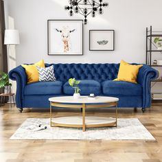 a living room with blue couches, yellow pillows and pictures on the wall above