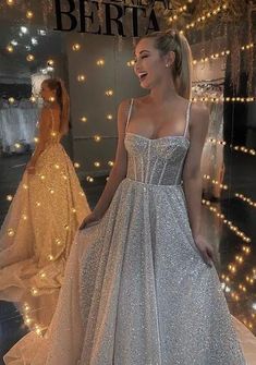 a woman standing in front of a mirror wearing a silver dress