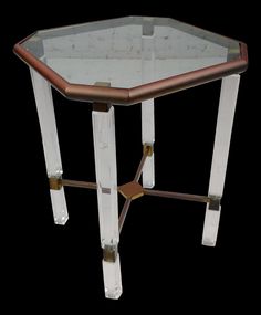 an octagonal glass and metal table with gold trimmings on the legs, against a black background