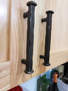 two black iron handles on wooden cabinets in a kitchen