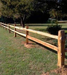 a wooden fence in the middle of a grassy field