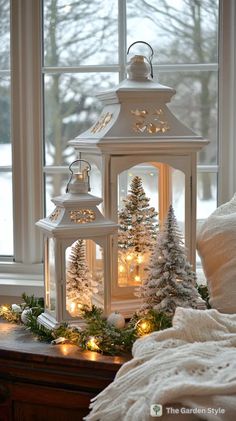 a white lantern with christmas trees and lights on it in front of a snowy window