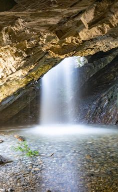 a small waterfall is coming out of a cave