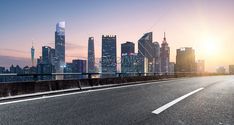 an empty highway with the city skyline in the background